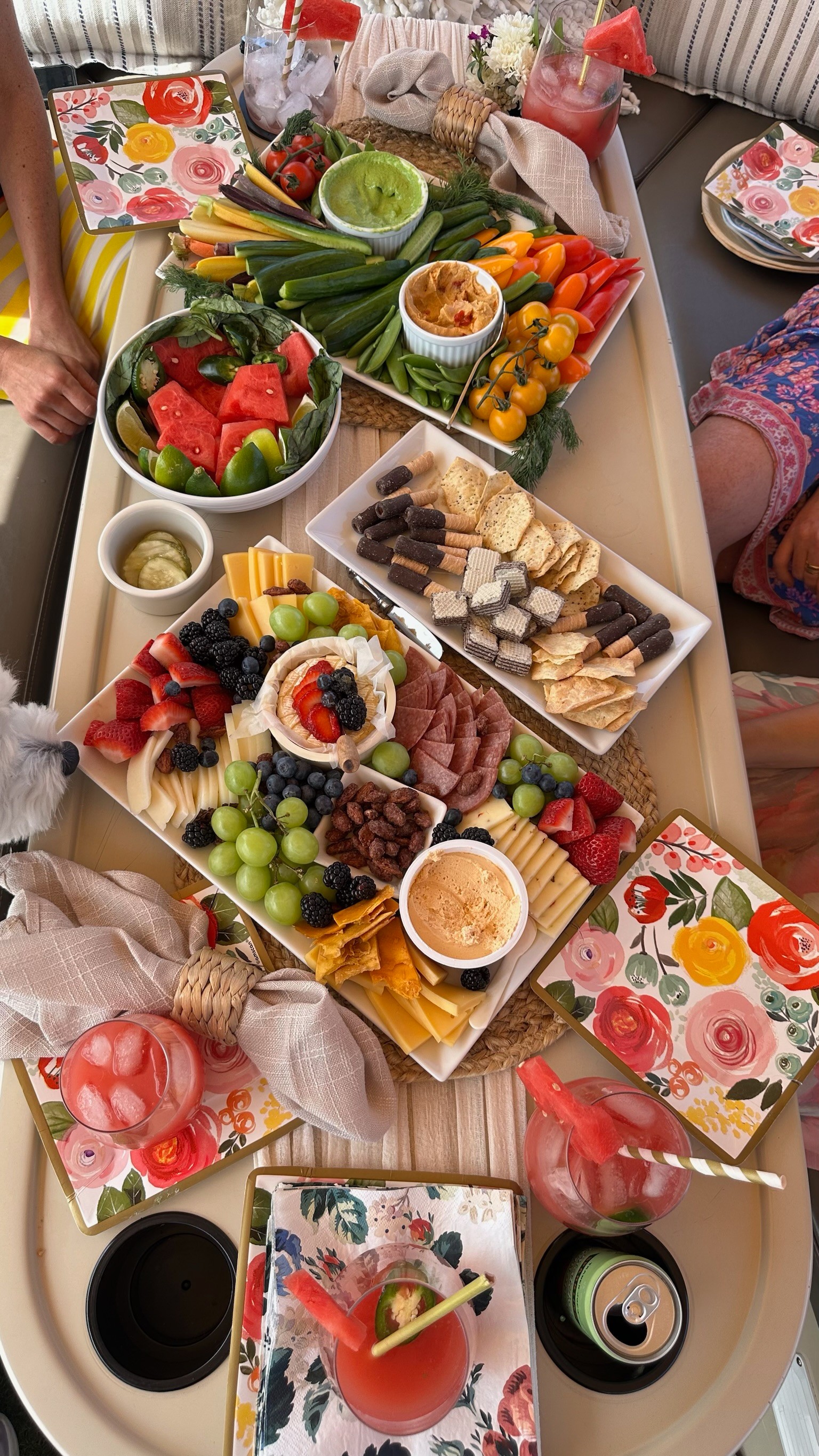 Table with various fruits, vegetables, and snacks, surrounded by colorful napkins and cups, viewed from above.