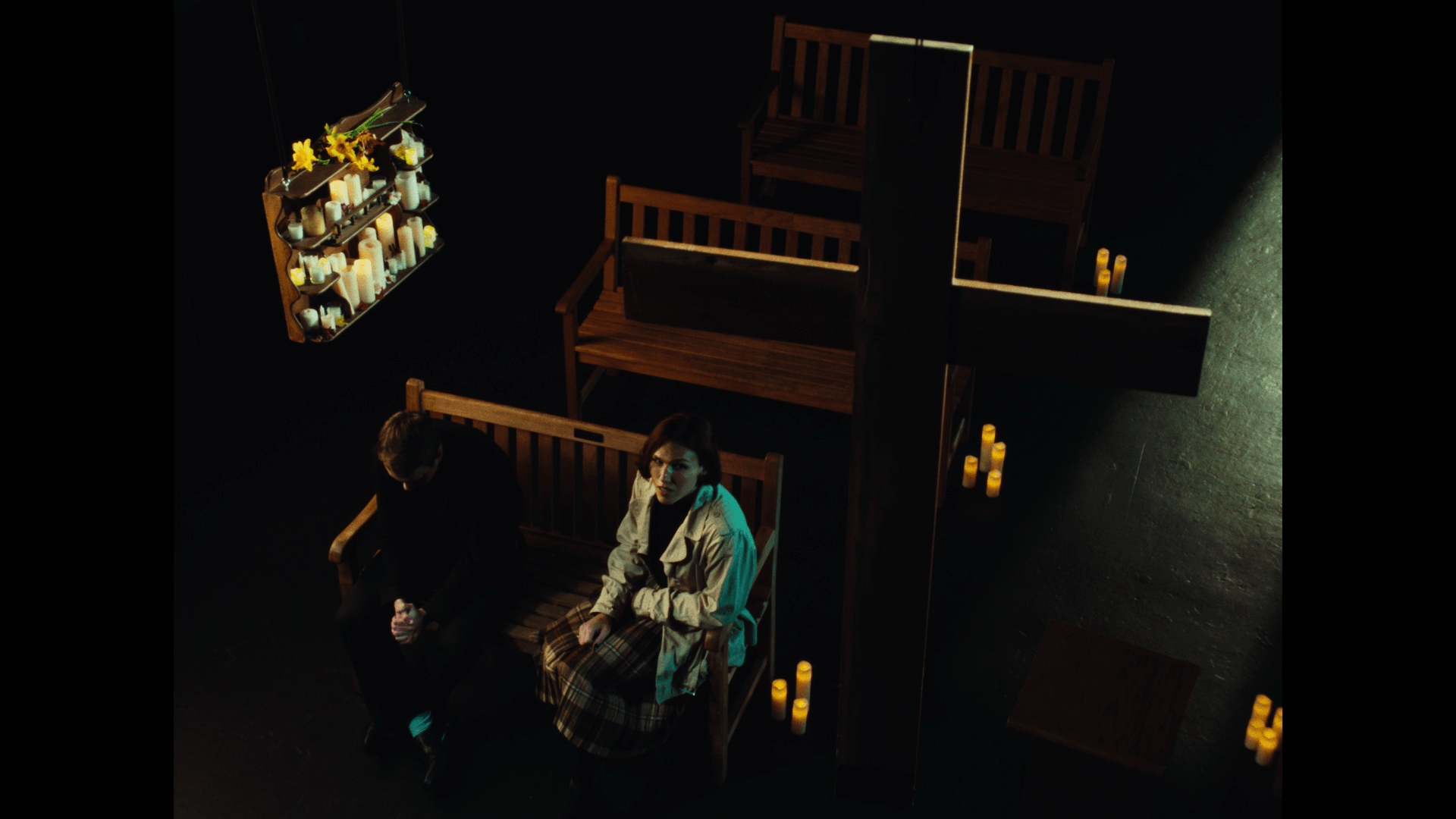 Two people sitting in a dimly lit room with candles and a bookshelf, viewed from above.