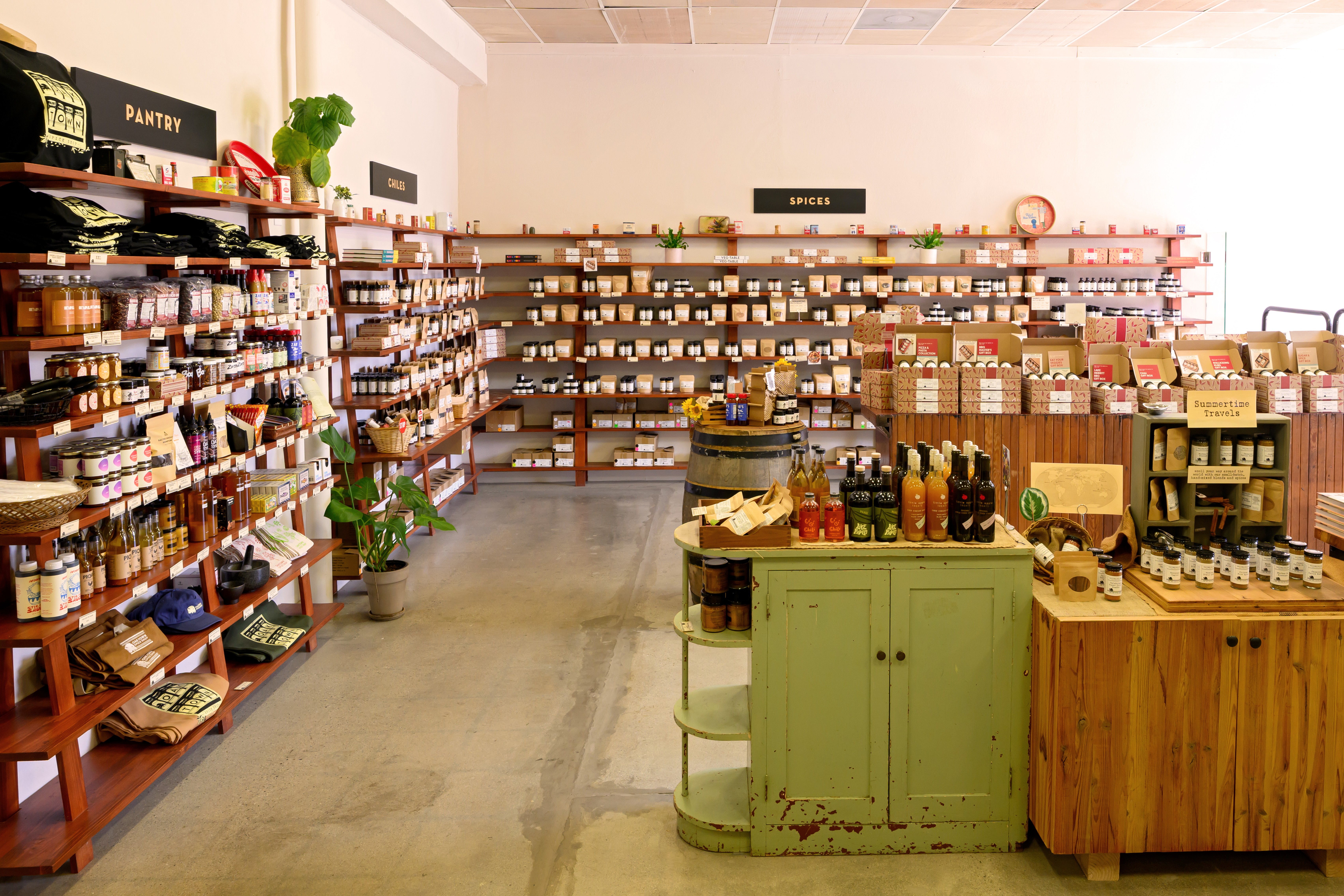 Interior of a store with shelves filled with jars, bottles, and boxes, and a green counter in the foreground.