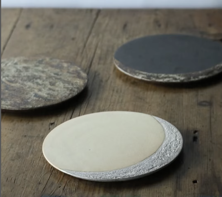 Three oval-shaped stones on a wooden surface, with one stone in the foreground and two in the background.