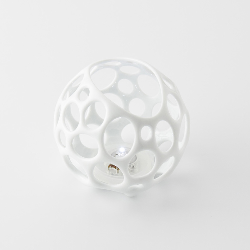 White spherical object with circular holes, small animal inside, on a white background.
