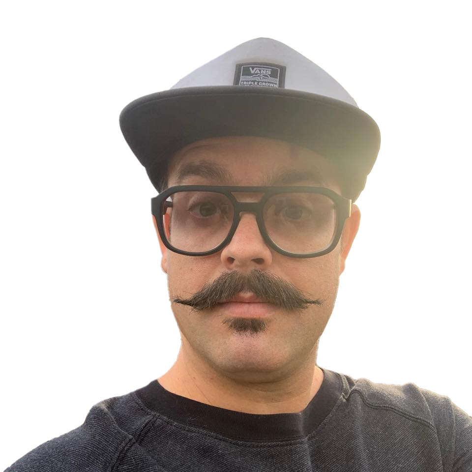 Person with glasses, mustache, wearing a cap, and a dark shirt, looking at the camera against a white background.