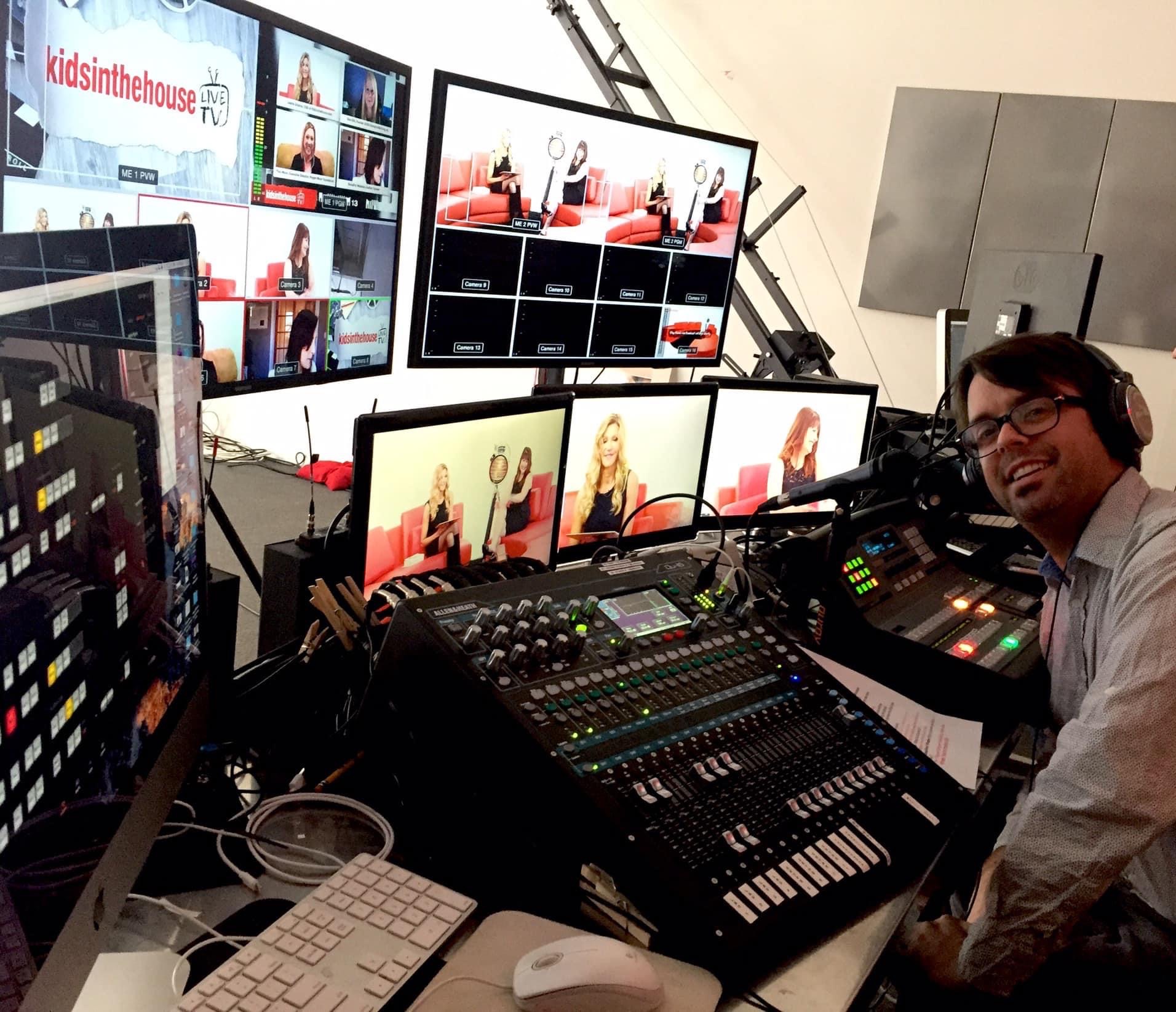 Person with headphones operating a video control panel with multiple monitors displaying various images and videos.