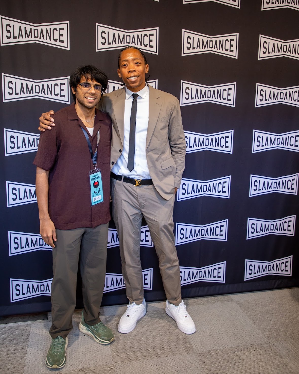 Two men standing together in front of a backdrop with 'SLAM DANCE' logos, smiling, one with arm around the other.
