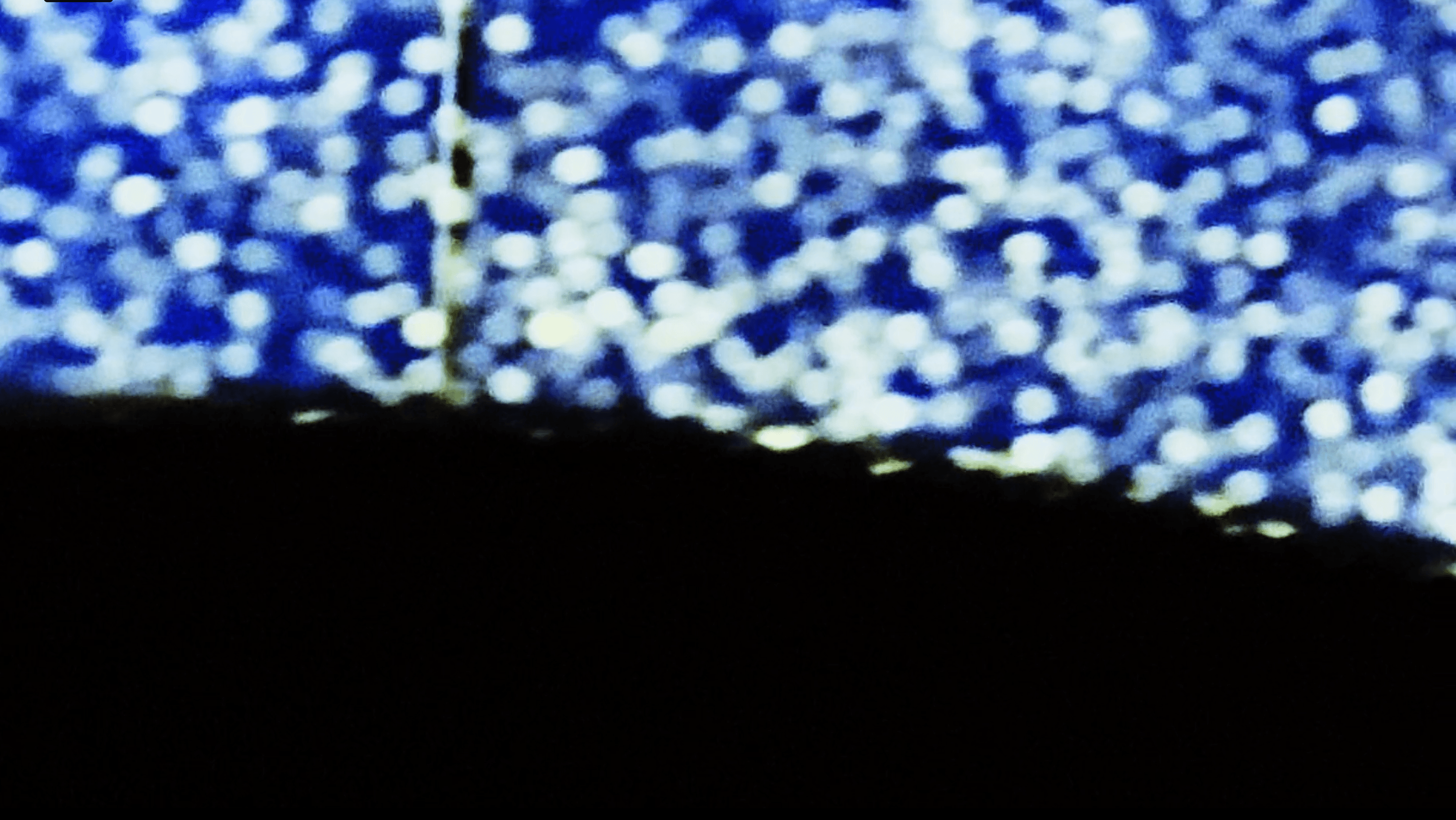 Close-up of a surface with blue and white bokeh lights, and a dark area at the bottom.