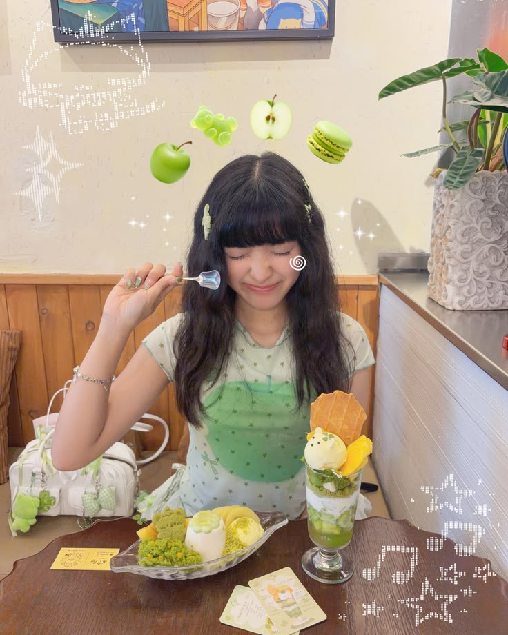 Young girl with long dark hair smiling with eyes closed, holding a spoon, surrounded by desserts and green floating objects, in a cozy room.