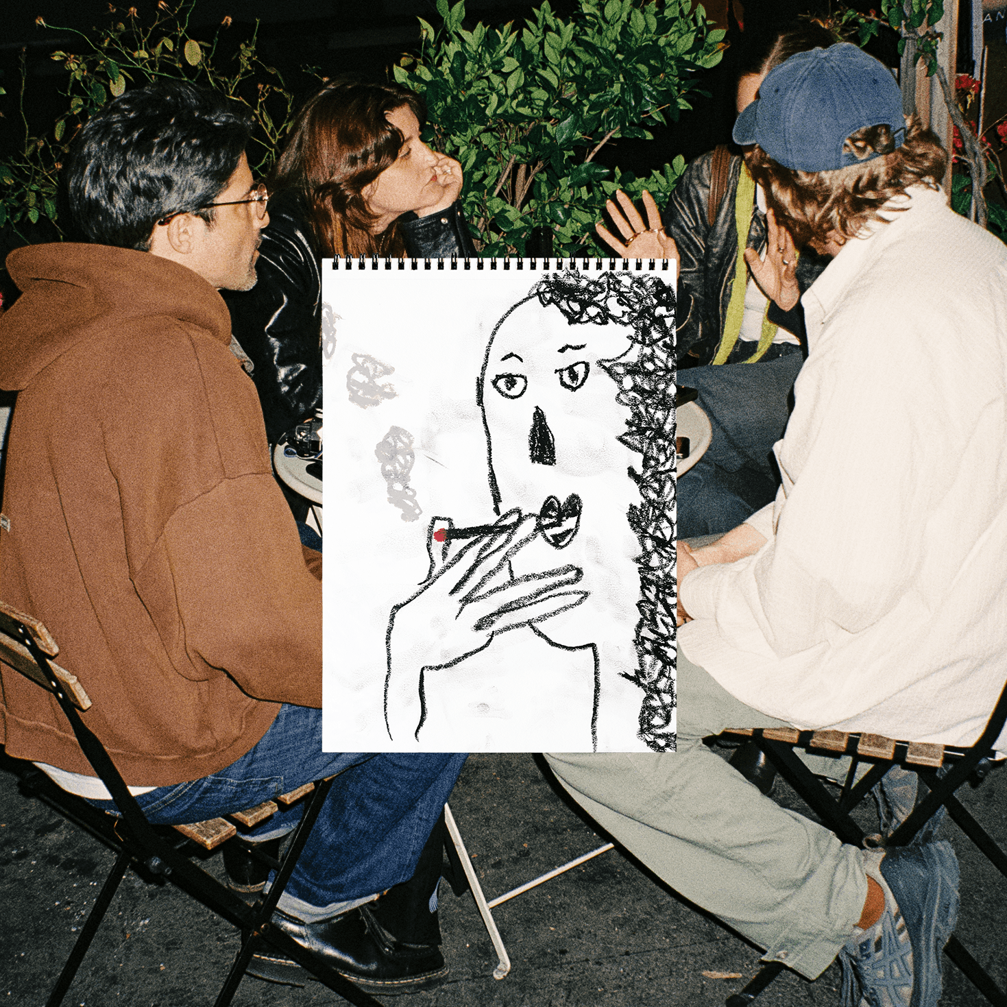 Four people sitting in a circle outdoors, engaged in conversation, with a drawing of a face and hand in the foreground.