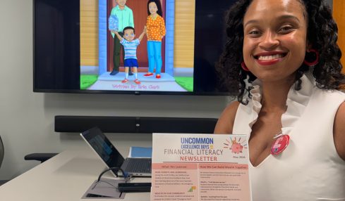 Woman sitting at desk with a menu, TV screen showing animated characters, and a tablet displaying a colorful image.